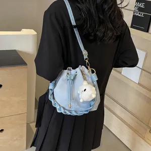 Bolso cubo azul claro con asa trenzada y colgante de peluche lindo para mujeres elegantes.