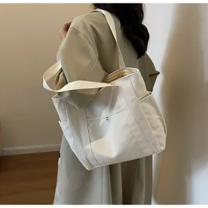 Detail view of large capacity cream canvas tote bag with shoulder straps and side pockets.