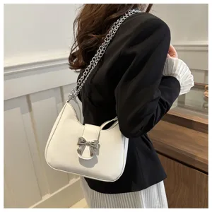 Stijlvolle witte schoudertas voor dames met een chique metalen strik en kettingriem.