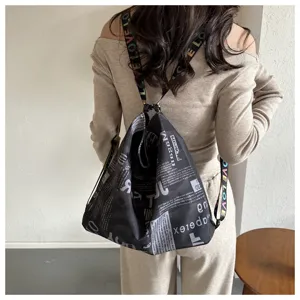Detail shot of a black newspaper print casual backpack with stylish letter straps.