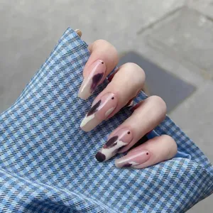 Primer plano de uñas postizas largas con elegante diseño de vaca morada y base nude.