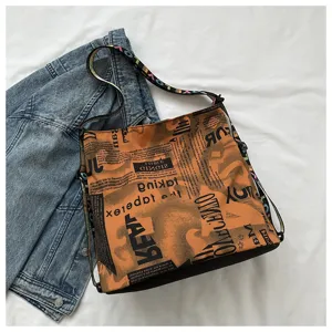 Detail view of casual oxford cloth shoulder bucket bag with stylish newspaper print and strap.