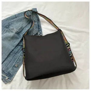 Detailed view of the casual black nylon bucket shoulder bag featuring colorful strap design.