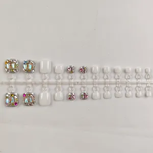 Vista detallada de uñas postizas para los pies con pedrería en soporte de plástico.