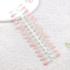 Vista de detalle de uñas postizas degradadas, exposición de tiras en rosa y verde menta.