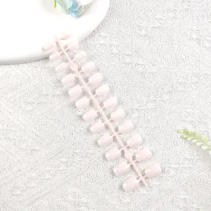 Primer plano detallado de tiras de uñas postizas rosa claro sobre una superficie de exhibición blanca.