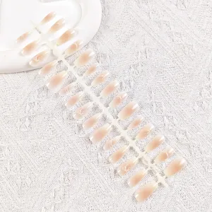 Uñas postizas degradadas nude con detalles de lazos blancos en tiras de plástico.