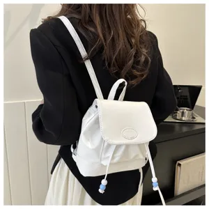 Vue détaillée d'un élégant mini sac à dos blanc avec cordon de serrage et perles mignonnes.
