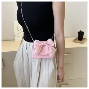 Pink bow crossbody bag detail, cute mini leather shoulder bag with chain strap and bow.