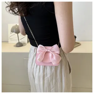 Detailed view of women pink crossbody bag with sheer bow and gold chain on model's back.