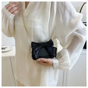 Chic black crossbody bag for women with elegant bow detail and gold chain strap fashion style.