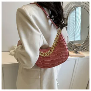 Vista detallada del elegante bolso de hombro rosa texturizado con una llamativa cadena dorada.
