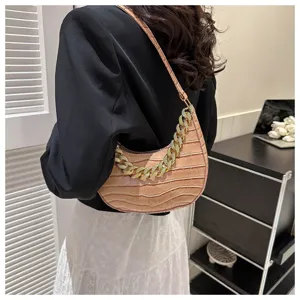 Vista detallada del elegante bolso de hombro con textura de cocodrilo rosa y cadena dorada gruesa.