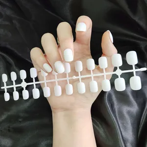 Detailweergave van matte witte korte ronde neppe nagels op een plastic displaykaart.