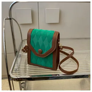 Gros plan sur le sac téléphone vert et marron sur étagère métal, détail tendance.
