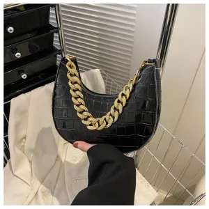Primer plano detallado del elegante bolso negro de cocodrilo con cadena dorada gruesa.