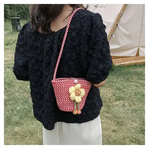 Summer woven mini bucket bag detail showing red pattern and cute yellow flower charm pendant.