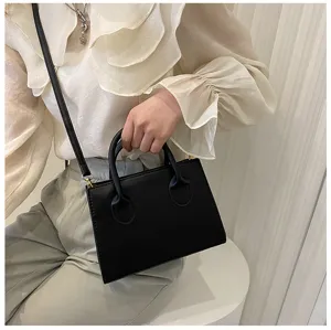 Detail de sac a main bandouliere noir minimaliste avec texture cuir lisse et poignee chic.