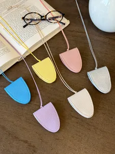 Detail view of colorful leather mini glasses pouch necklaces displayed neatly on wooden desk.