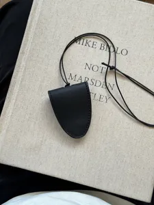 Vue détaillée du sac de cou géométrique en cuir noir, collier pendentif minimaliste.