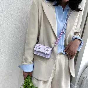 Women mini purple crossbody shoulder bag with chunky chain strap worn by model in suit.