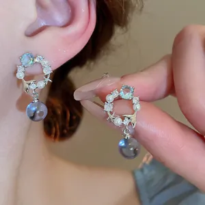 Detailaufnahme von Silberohrringen mit blauen Kristallen und Perlen, maritimes Design.