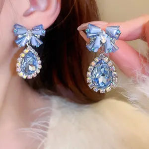 Exquisites Nahbild der funkelnden blauen Kristall Schleife Tropfen Ohrringe Detail.