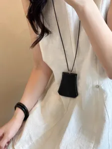 Black leather clochette necklace pendant stylish sweater chain geometric glasses pouch accessory.