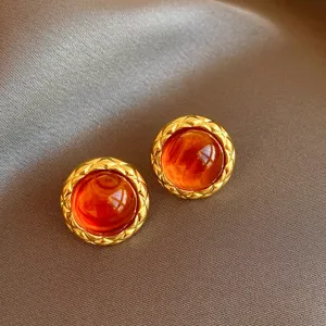 Detailed shot of vintage gold-plated round earrings with amber resin and quilted pattern.