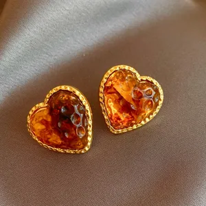 Close-up detail of retro brown resin heart earrings with textured gold metal border.