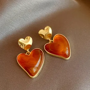Close-up detail of retro brown resin heart earrings with gold plating, elegant aesthetic jewelry.