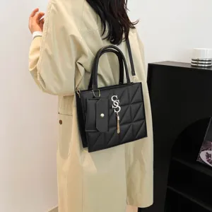 Borsa a tracolla trapuntata nera alla moda con doppi manici e ciondolo metallico chic.