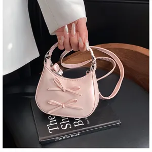 Nahaufnahme des süßen rosa Halbmond-Handtasche mit niedlichen Schleifen und feinen Griffen.