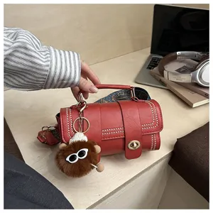 Vue détaillée du sac à main rétro rouge pour femme avec sangle large et porte-clés en peluche.
