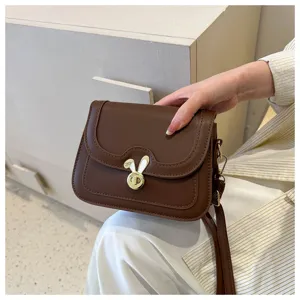 Close up detail of stylish brown crossbody small square bag featuring cute rabbit lock clasp.