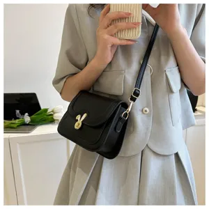 Close-up detail of trendy black crossbody bag featuring a cute metallic bunny ear clasp.