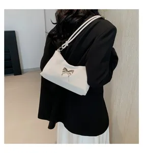 Vue détaillée d'un sac porté épaule blanc élégant avec décor papillon métallique unique.