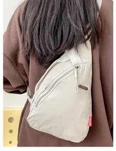 Vista detallada del bolso cruzado minimalista de lona con bolsillo diagonal y etiqueta metálica.