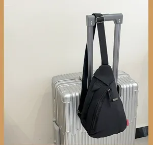 Vista detallada del bolso bandolera minimalista negro colgado de la maleta, mochila casual.