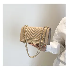 Détail de sac bandoulière matelassé chic, design beige élégant avec quincaillerie.