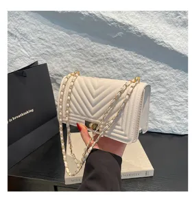 Vue détaillée du sac bandoulière blanc matelassé en V avec chaîne élégante et fermoir chic.