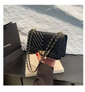 Détail du sac bandoulière matelassé noir, motif chevron chic avec fermoir métallique doré.
