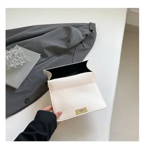 Détail de sac à bandoulière blanc minimaliste montrant le design élégant et le fermoir doré.