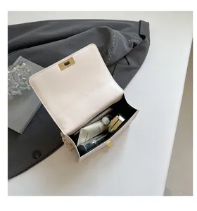 Détail de sac bandoulière en cuir blanc avec chaîne, vue intérieure petit sac carré élégant.