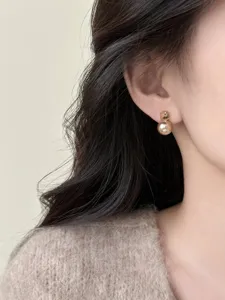 Detailed view of elegant champagne pearl earrings featuring chic square zircon and polished gold.