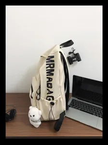 Detail view of minimalist student canvas backpack with side letter print and cute bear.