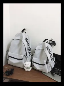 Detail view of minimalist solid color school backpacks in light gray with side pockets.