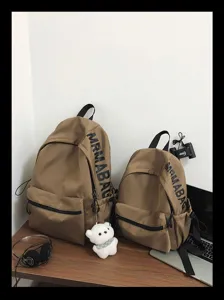 Detail view of minimalist solid color canvas backpacks with side letter print and cute pendant.
