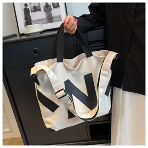 Detailed view of casual canvas tote bag with black letter print, single shoulder strap.