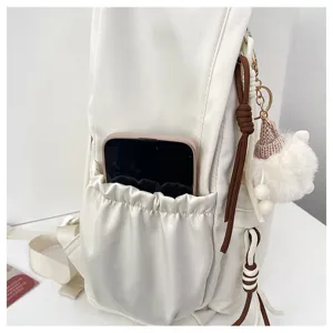 White backpack detail view with side pocket, brown cords and cute plush ball pendant stylish.